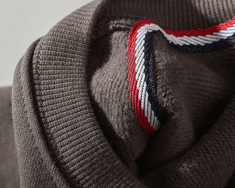 Close-up of brown sweatshirt fabric with red, white, and blue striped detail, showcasing the cozy texture and stylish design.